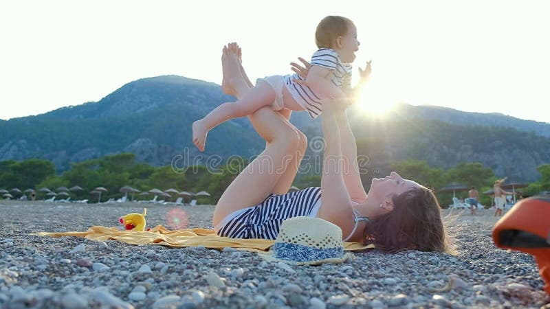 有她的小女婴的年轻母亲获得在海滩的乐趣在夏日